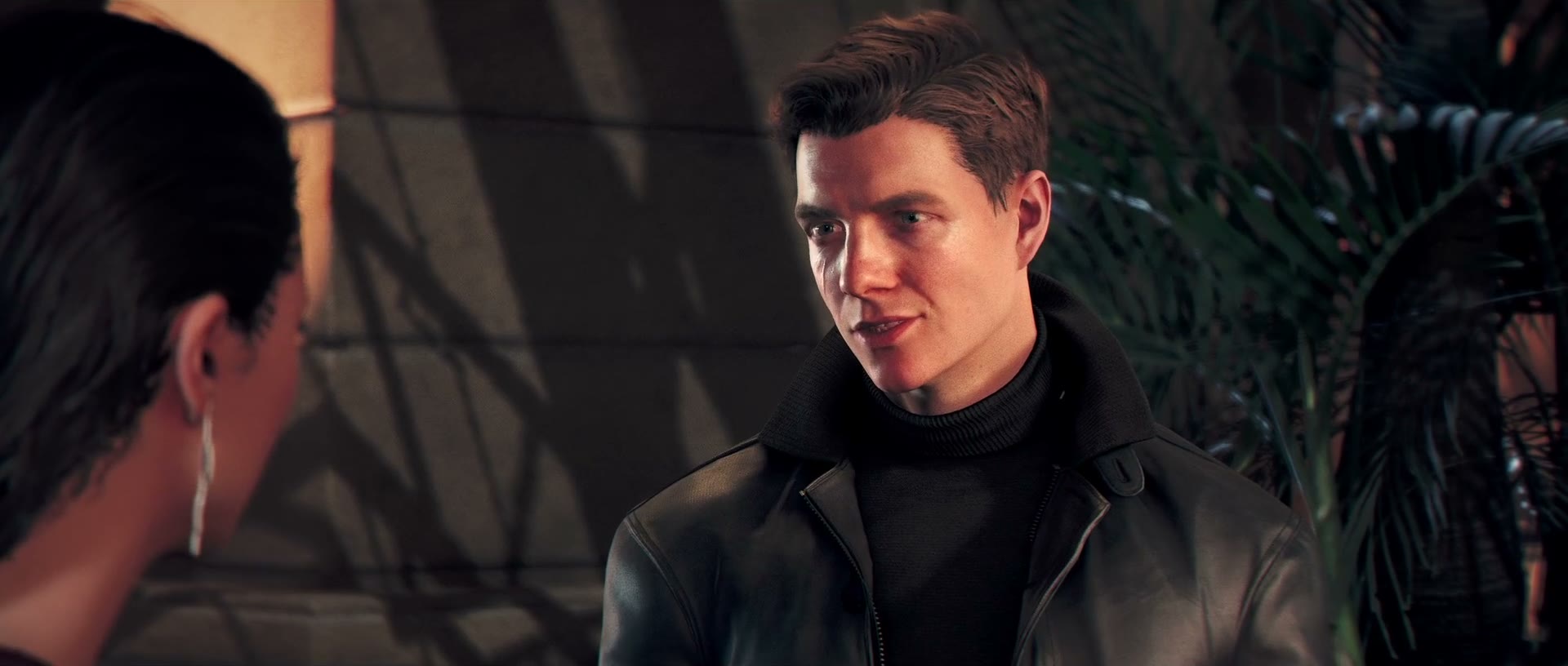 Official 007 First Light screenshot — a young James Bond in a leather jacket, smiling during a conversation in warm, palm-lined light.