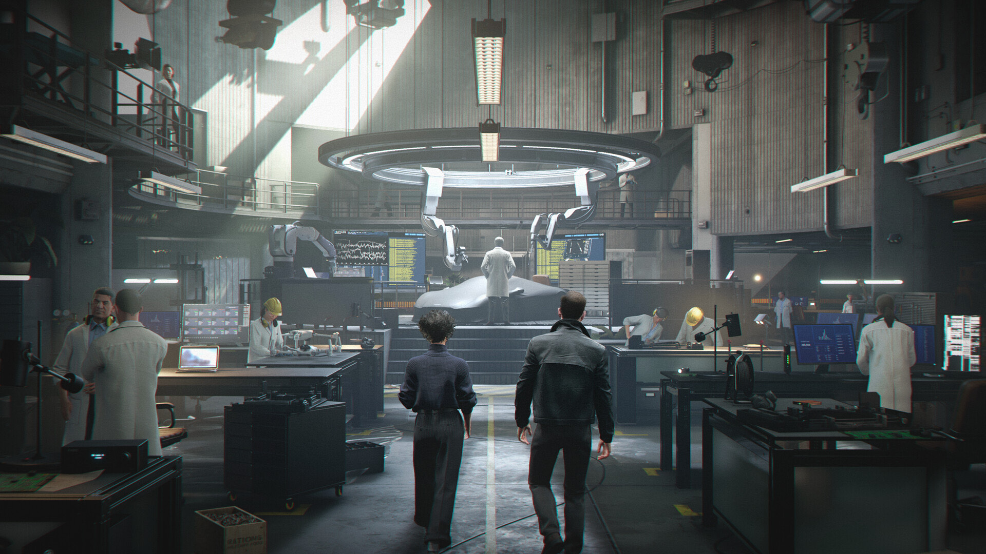 Two figures walking into a large technical workshop as staff work at lit benches.